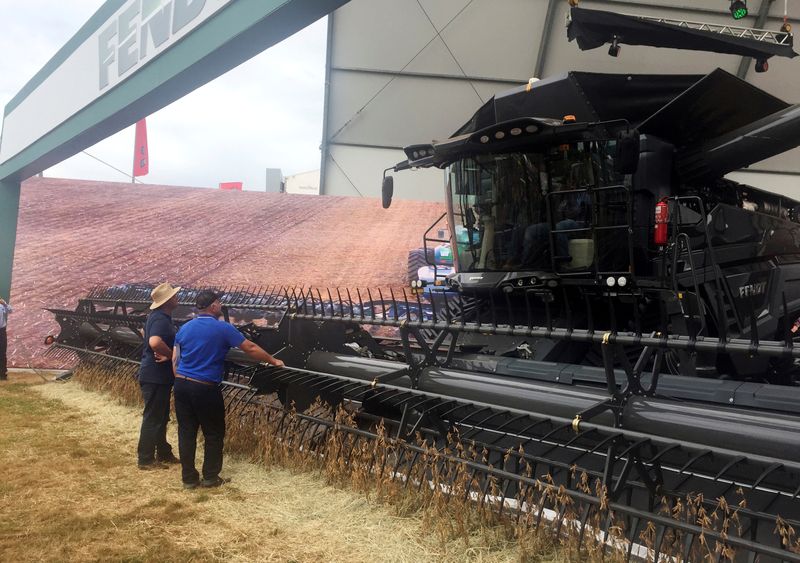 Farmers look at a large grain harvester during the Agrishow