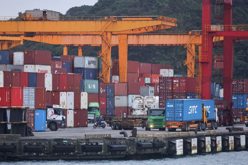 Cargo trucks work inside a container yard, in Keelung