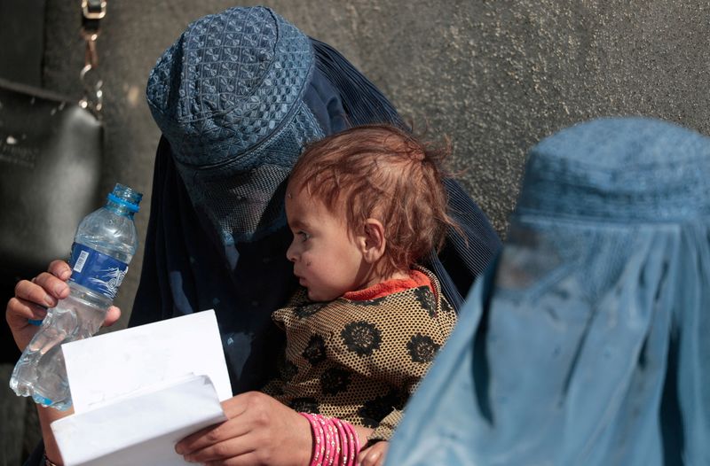FILE PHOTO: Displaced Afghan woman holds her child as she