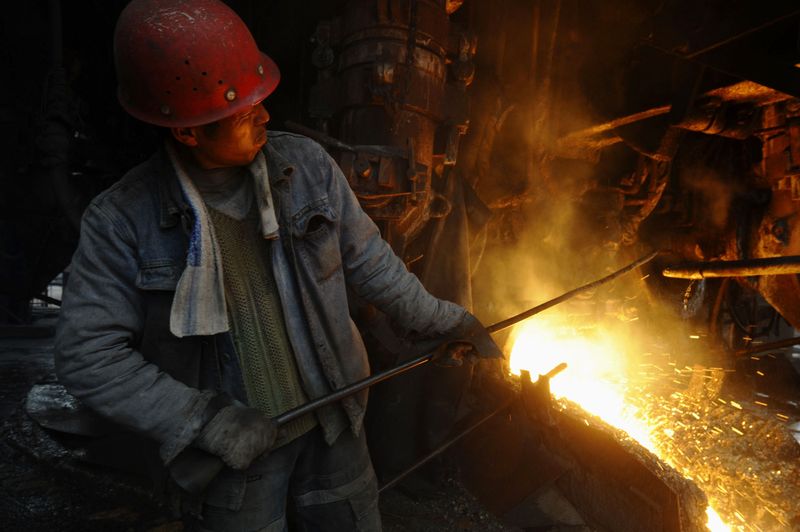 A labourer opens the door of a steel furnace to