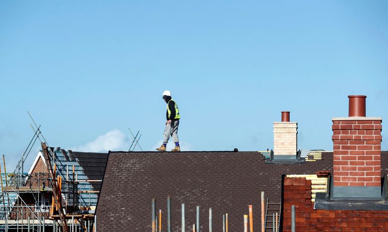 FILE PHOTO: A construction worker walks on a roof as