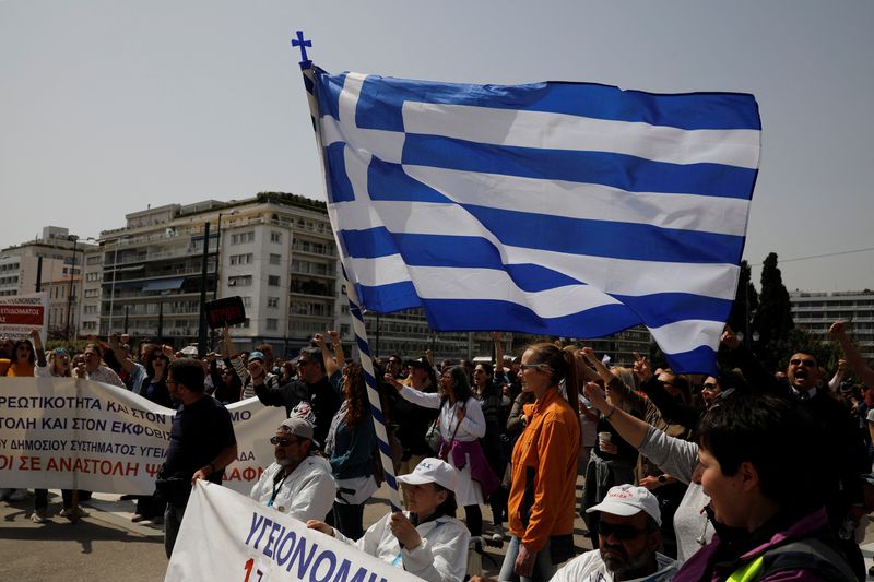 A woman holds a Greek flag as she takes part