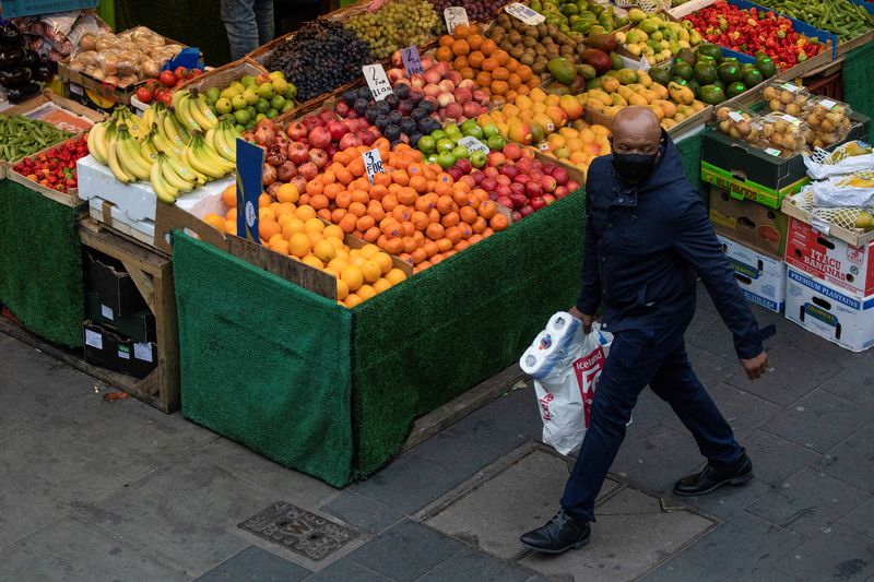 A man carrying toilet roll walks past a fruit and