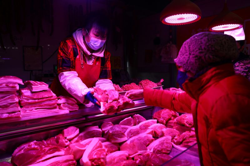 A customer buys pork at a meat stall inside a