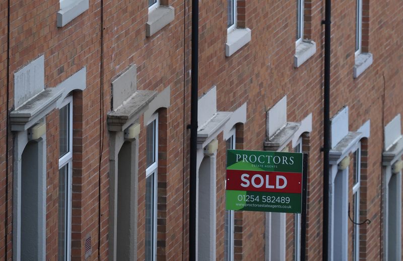 An estate agent’s board is displayed outside a house on