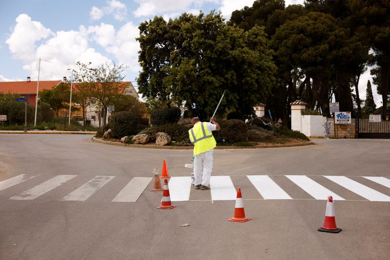 A worker paints a crosswalk in Ronda
