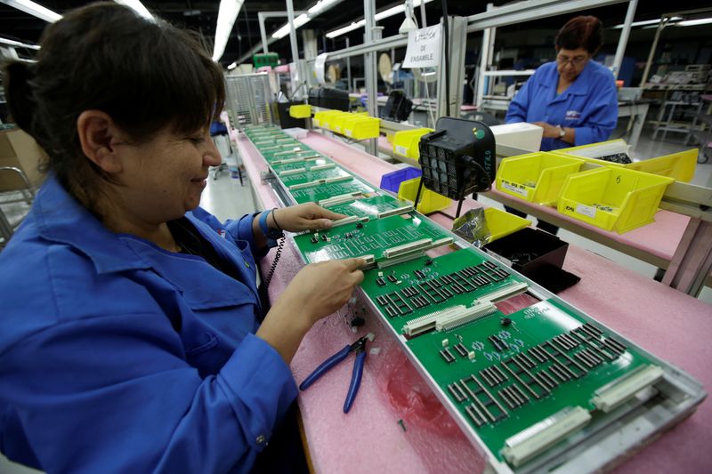Employees work on printed circuit boards at the assembly line