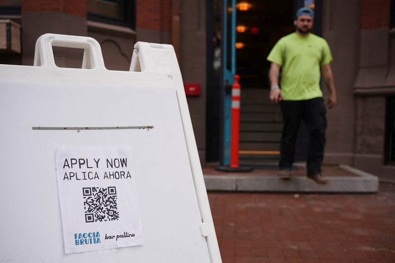 An “Apply Now” sign stands outside a new bar in