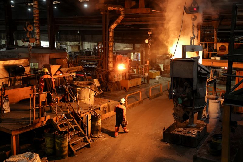 A worker walks past a crucible containing molten metal at
