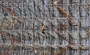 FILE PHOTO: Worker climbs a scaffolding at a construction site