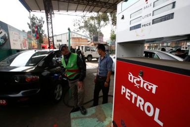 A petrol pump attendant (L) fills petrol for 99 NRS