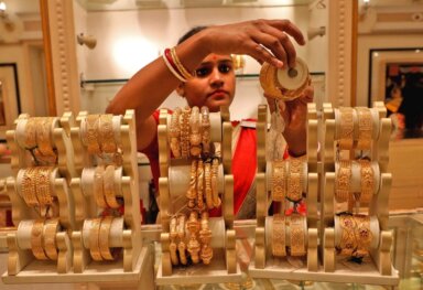 A saleswoman shows gold bangles to a customer at a