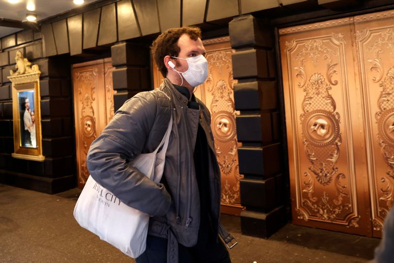 FILE PHOTO: A man in a protective mask walks past
