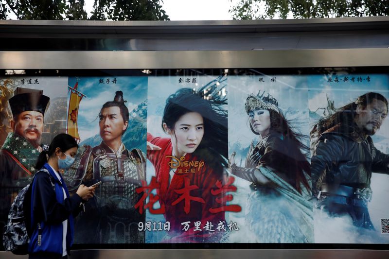 Woman walks past an advertisement promoting Disney’s movie “Mulan” at