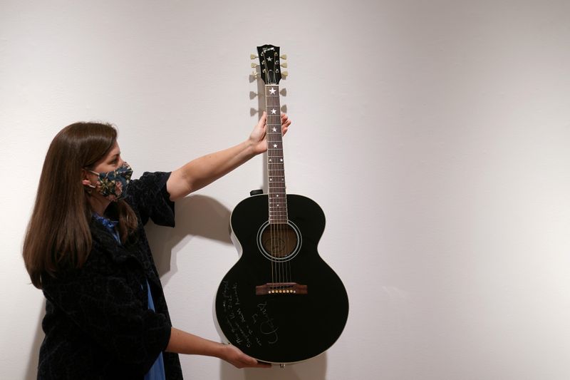 An employee of Christie’s auction house holds a guitar used