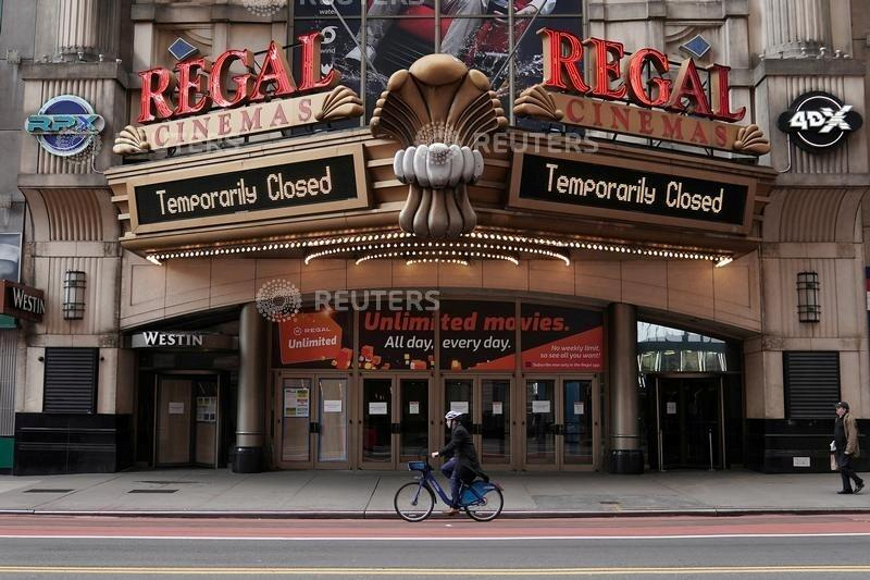 FILE PHOTO: A man cycles past a shuttered movie theater