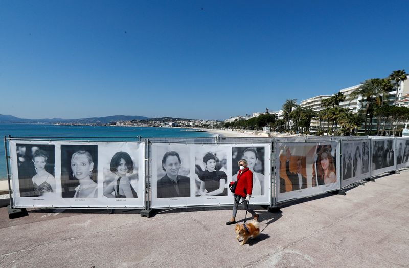 FILE PHOTO: A woman walks past photos of the Cannes