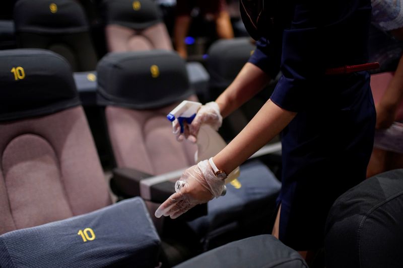 A staff member disinfects seats in a cinema as it