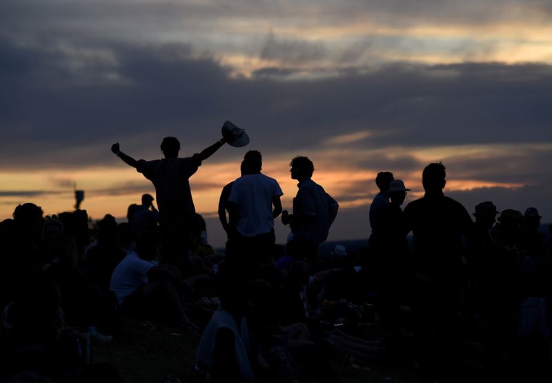 FILE PHOTO: Revellers dance as the sun sets during the