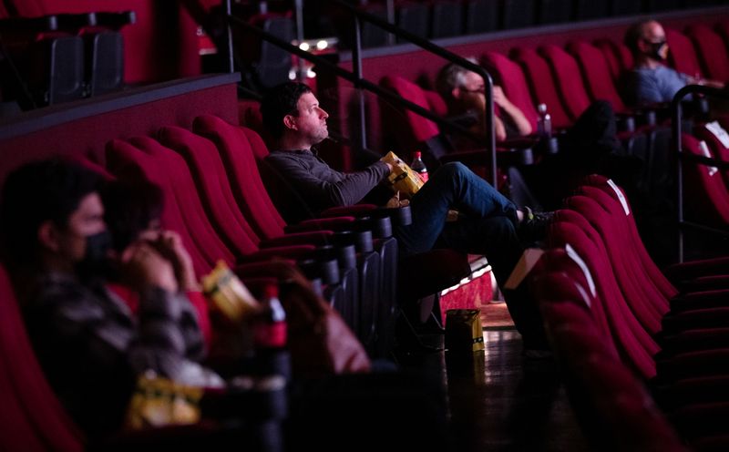 Moviegoers sit socially distanced as they wait for the movie