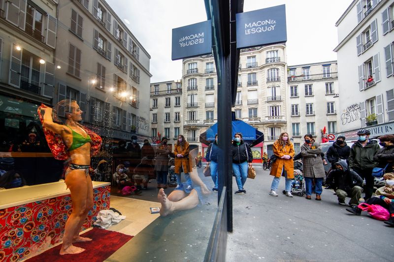 French actors perform a play behind store window in Paris