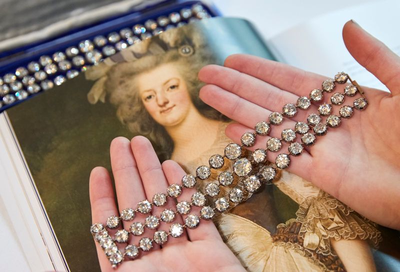 A staff displays a pair of diamond bracelets before their