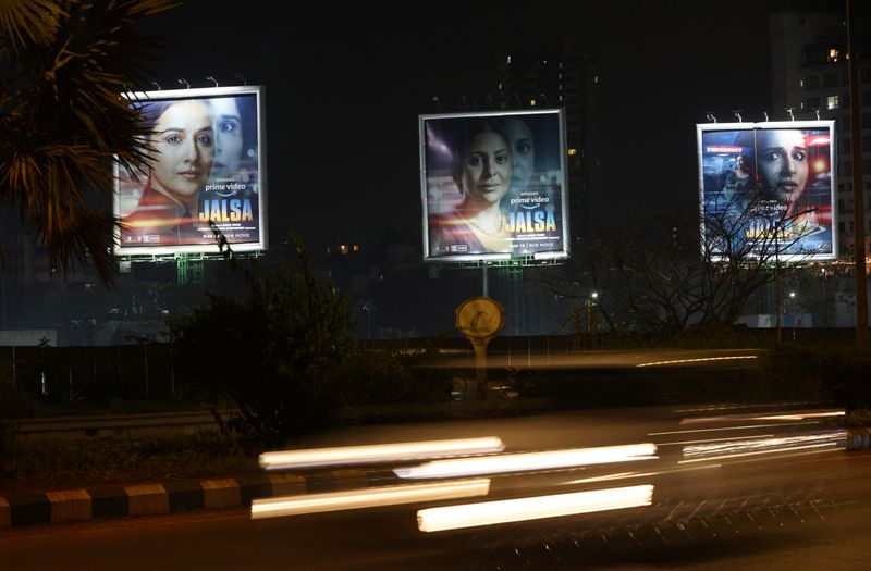 Traffic moves past a poster of upcoming Indian film “Jalsa”