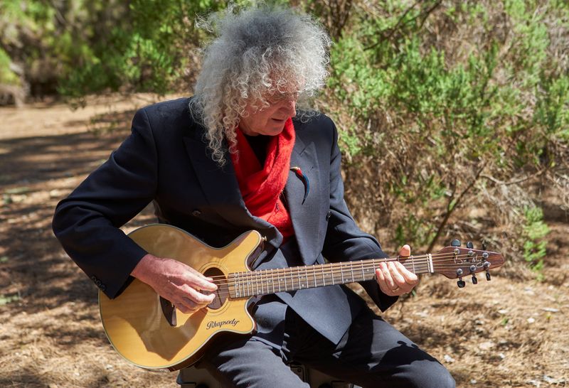 Musician Brian May plays the guitar while making a music