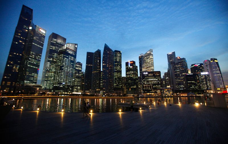 People walk past the skyline of Marina Bay central business