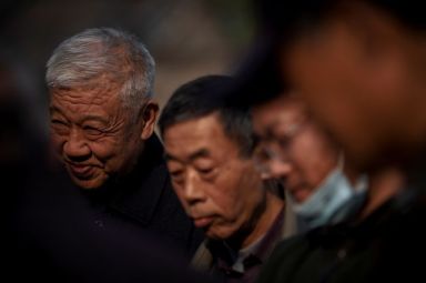 Elderly people watch a game of mahjong in Beijing
