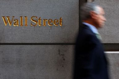 FILE PHOTO: A man walks along Wall Street in New