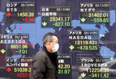 FILE PHOTO: A man walks past a stock quotation board
