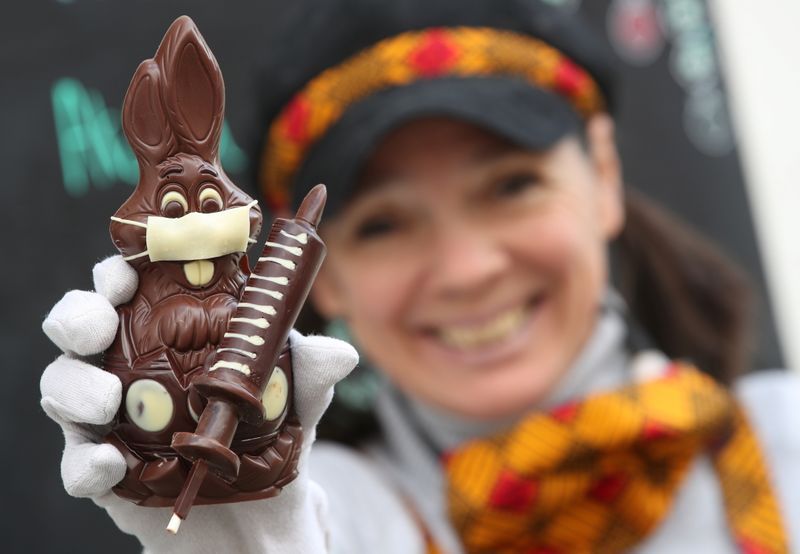 A chocolate bunny wearing a protective mask and holding a