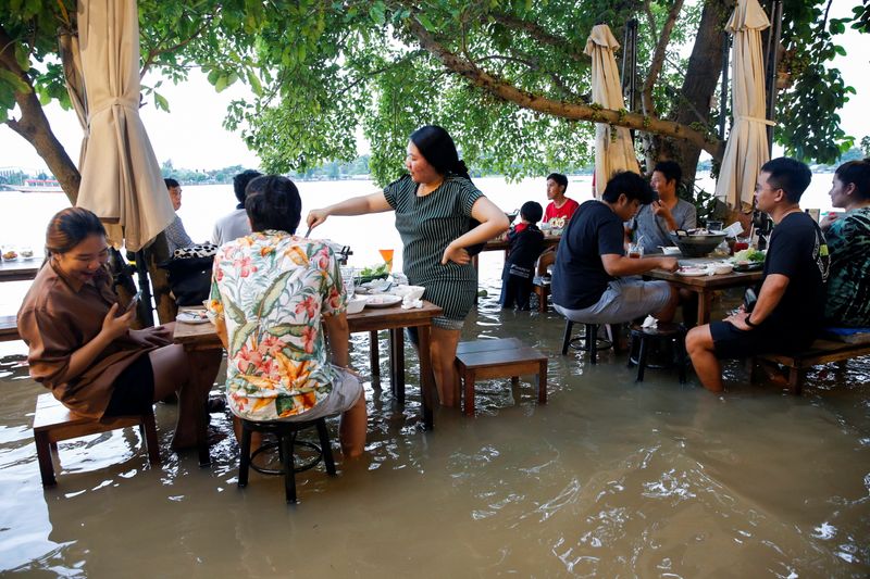People eat food at a flooded restaurant, where patrons stand