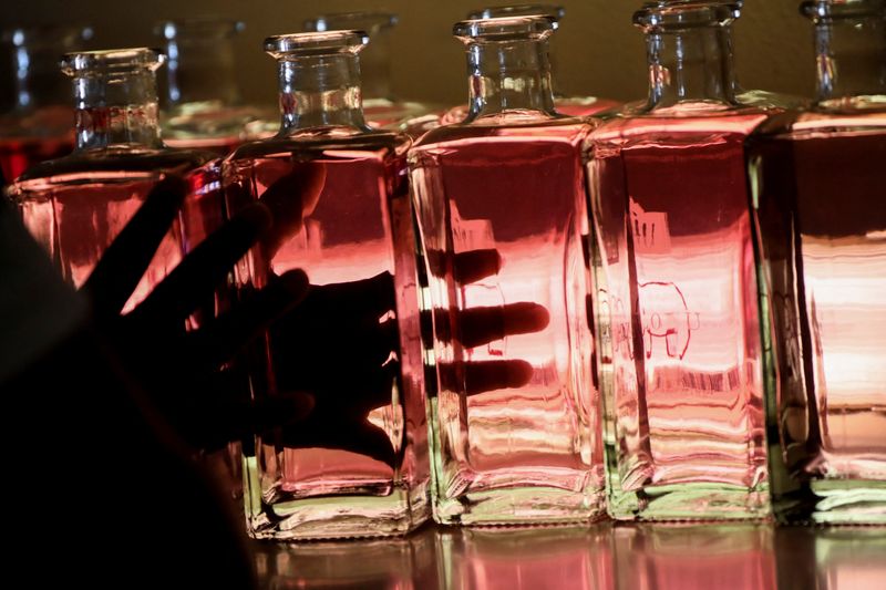 Staff member at Indlovu Gin moves bottles during bottling process,