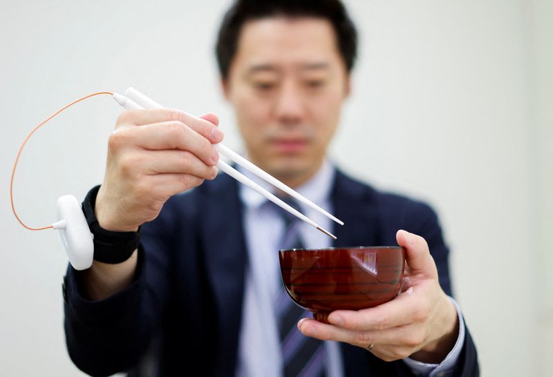An employee of Kirin Holdings demonstrates chopsticks that can enchance