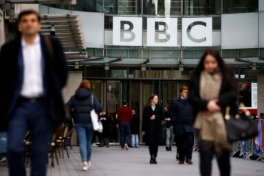 FILE PHOTO: Pedestrians walk past a BBC logo at Broadcasting