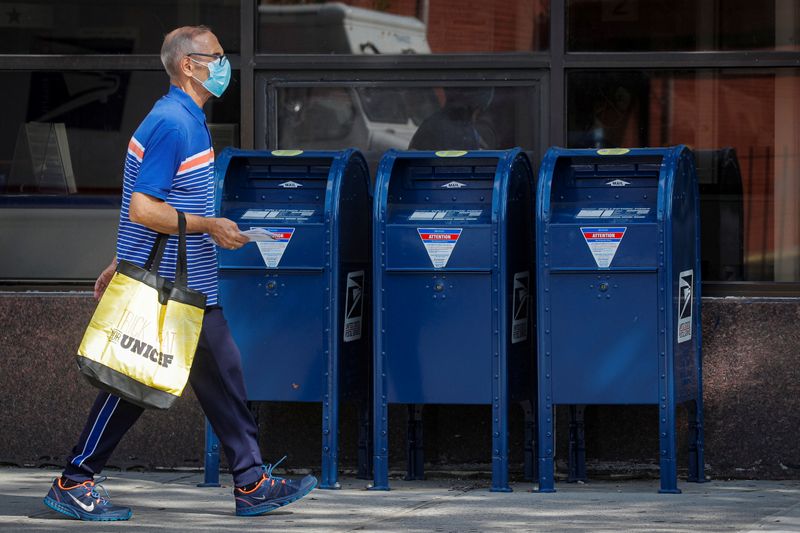 A man carries letters into a USPS post office in