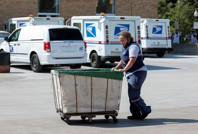 FILE PHOTO: A United States Postal Service (USPS) worker pushes
