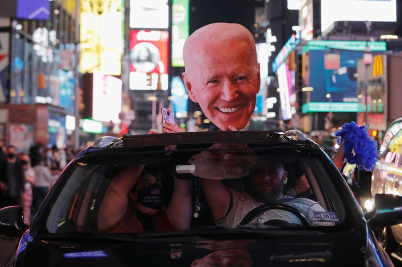 A Biden cutout is seen on a car, as people