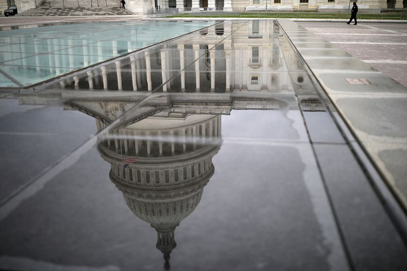 The U.S. Capitol Building is reflected on a marble seating