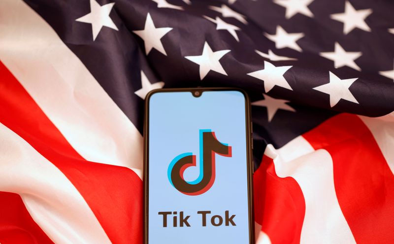Tik Tok logo is displayed on the smartphone while standing
