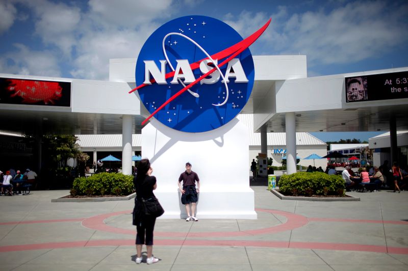 Tourists take pictures of a NASA sign at the Kennedy