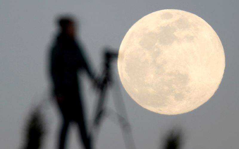 FILE PHOTO: A woman photographs the Pink Supermoon over mountain