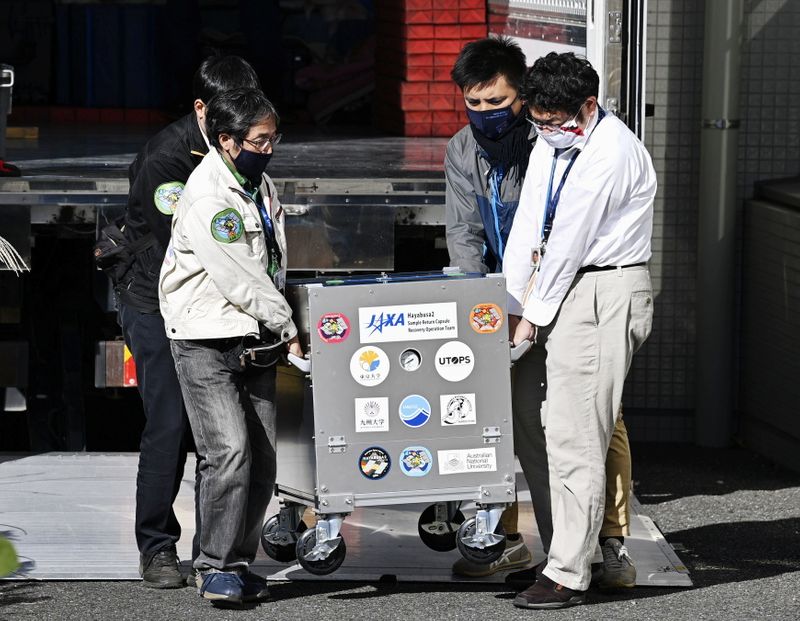 Japan Aerospace Exploration Agency’s (JAXA) staff carry a case containing