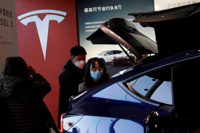 FILE PHOTO: Visitors wearing face masks check a China-made Tesla