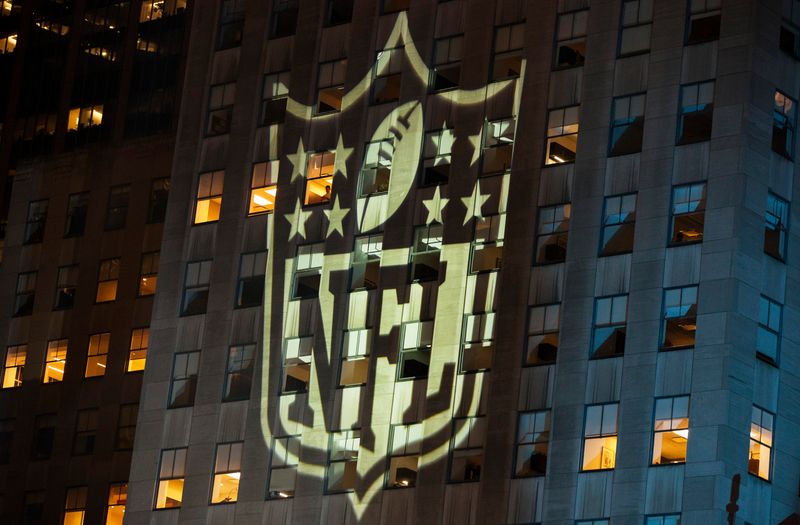A man stands at a window lit by the NFL