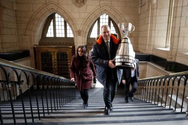 CFL commissioner Randy Ambrosie carries the Grey Cup trophy on