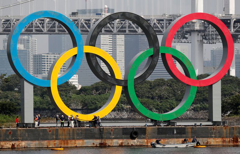 Workers prepare to carry the giant Olympic rings, which are