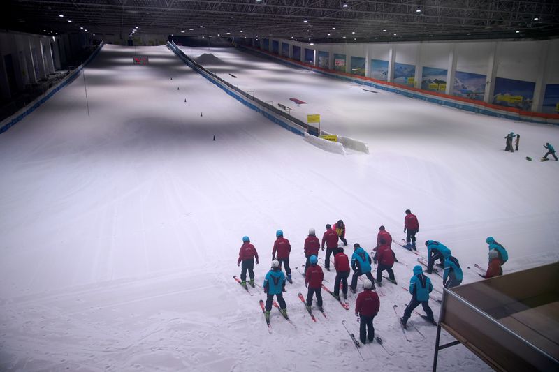 People warm up inside an indoor ski park at Qiaobo